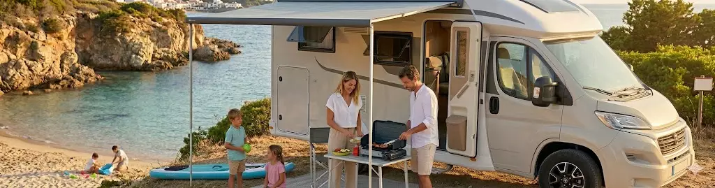 Famiglia si gode la vacanza davanti al camper in paesaggio con lago